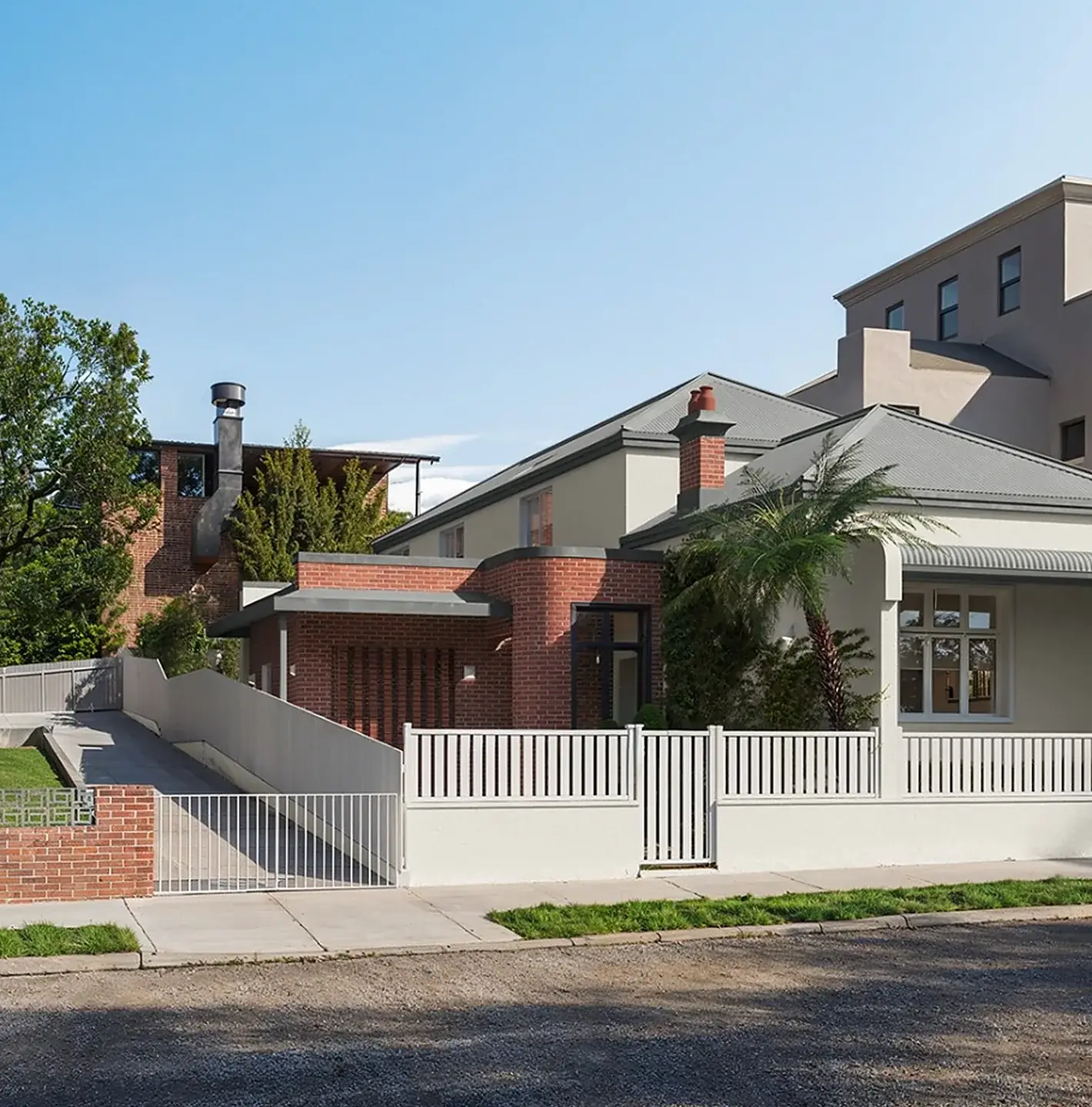 Elara in Annandale: a period cottage with a brick entry pavilion behind a white picket fence, with a palm at the street