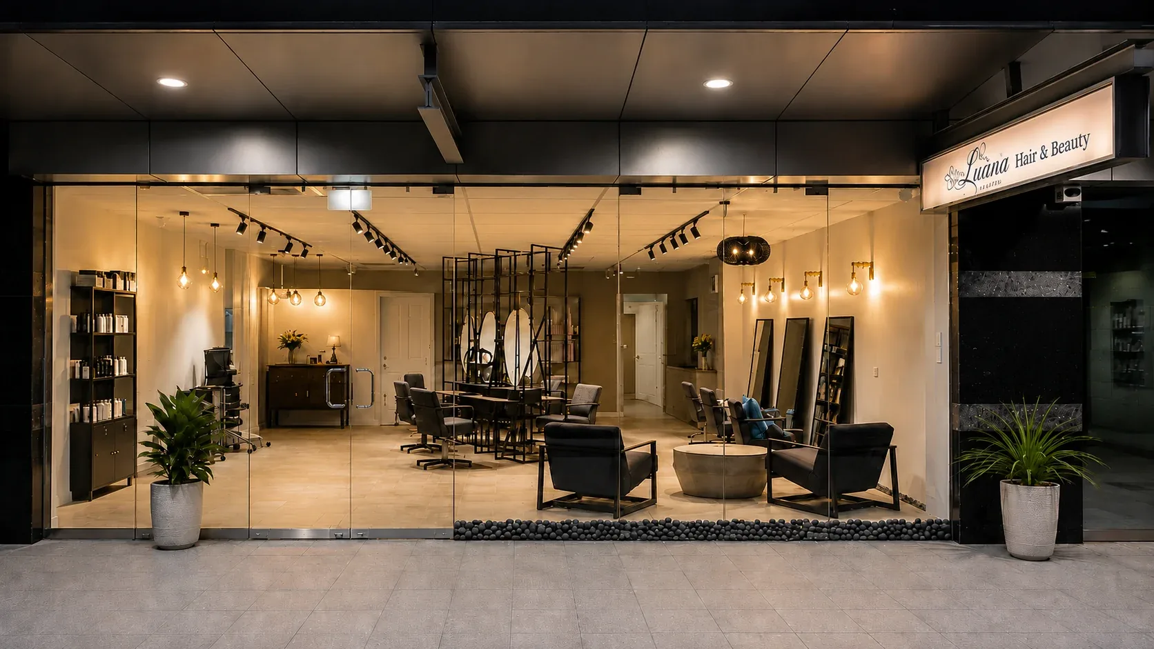 Luana Hair & Beauty shopfront in Waterloo at night: full-height glazing into a warm-lit salon with styling chairs and black shelving