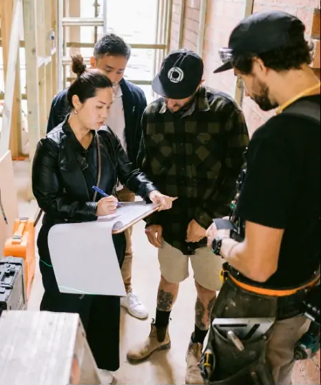 An OIC architect going over plans with three builders on a construction site