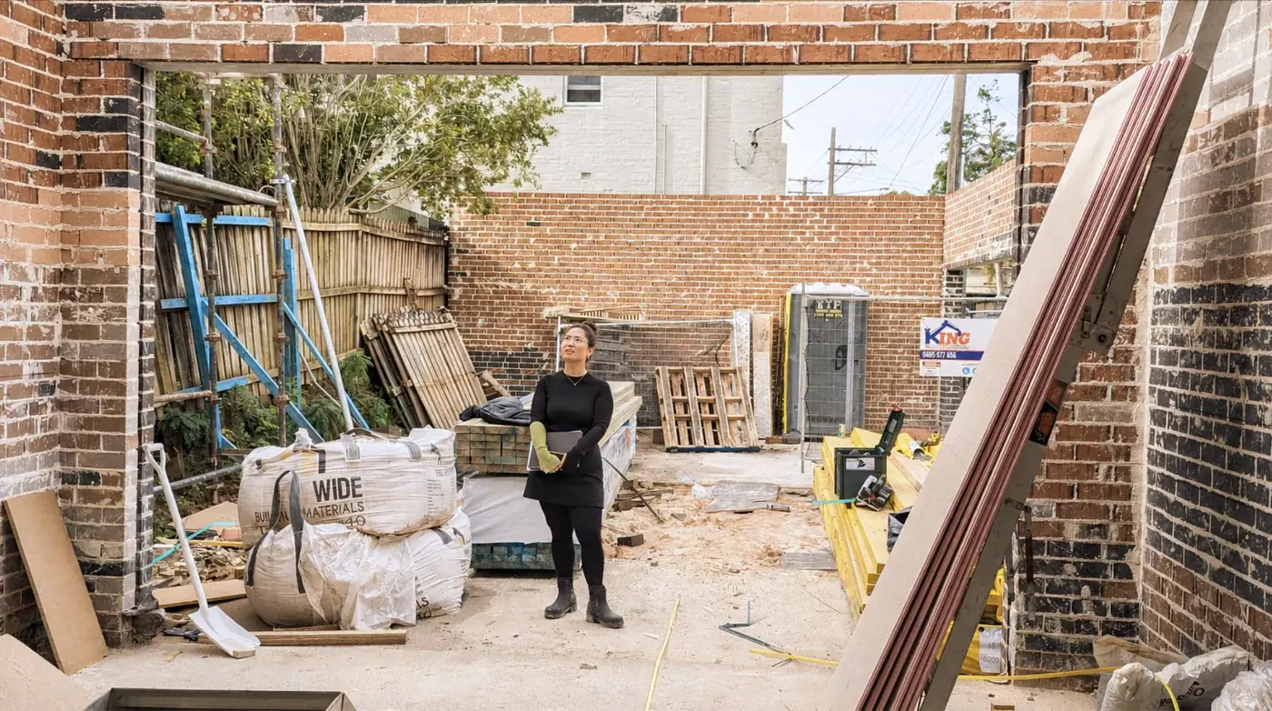 An OIC team member standing inside the brick walls of a house mid-demolition, assessing the property